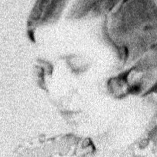 Woman seated at table, reading in a vintage-style room.