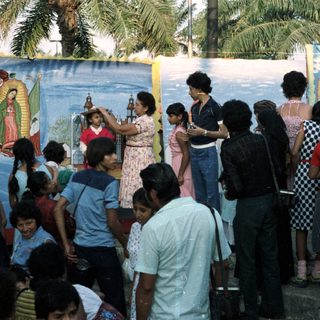 Group gathers before a mural, someone holds a statue.
