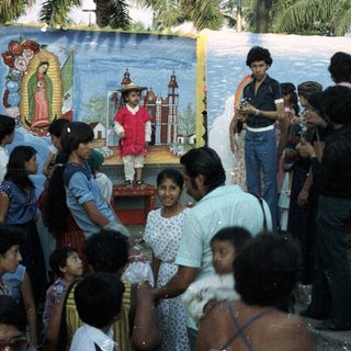 Group gathers around a child in costume near mural.