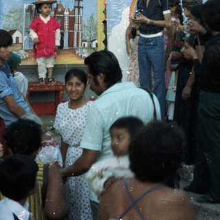 Group gathers around a child in costume near mural.