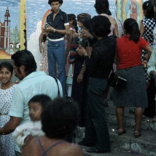 Group gathers around a child in costume near mural.