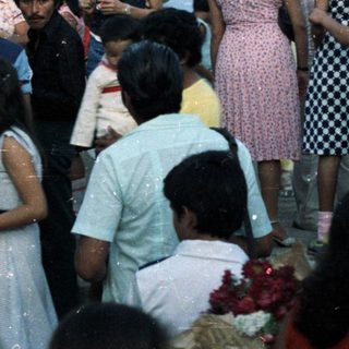 Group of people gathered before a religious mural outdoors.