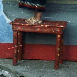 Girl stands on table before a mural, likely religious.