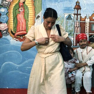 Woman, child, and man posed before a mural.