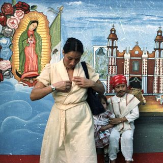 Woman, child, and man posed before a mural.