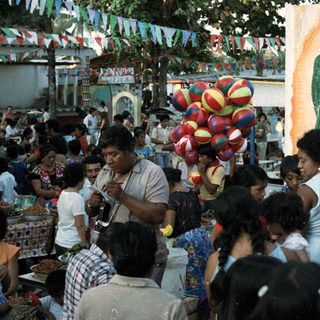 Crowded gathering near an altar with decorations and balloons.