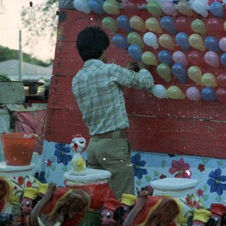 Children playing a game involving balloons and buckets.