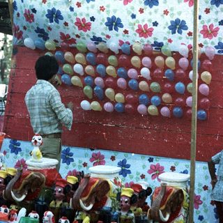 Man arranges ceramic roosters for a game display.