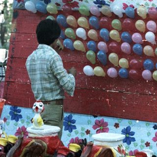 Man arranges ceramic roosters for a game display.