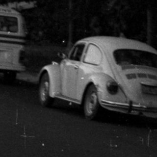 Crowd gathers on a road with vehicles and smoke.