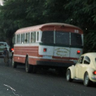 Man lighting fireworks on a road with onlookers.