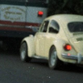 Man lighting fireworks on a road with onlookers.