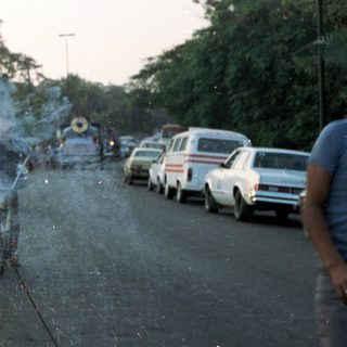 Man sparks fireworks on a road with onlookers.