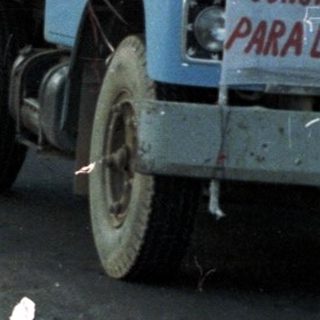 Parade or procession with trucks, people, and festive decorations.