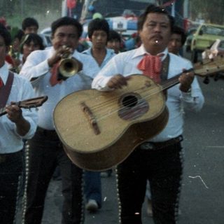 Parade or procession with musicians and onlookers.