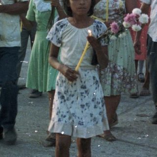 Procession with musicians and candle-bearers in a tropical setting.