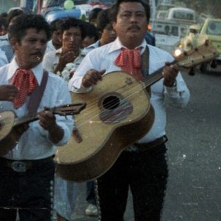 Procession with musicians and candle-bearers in a tropical setting.