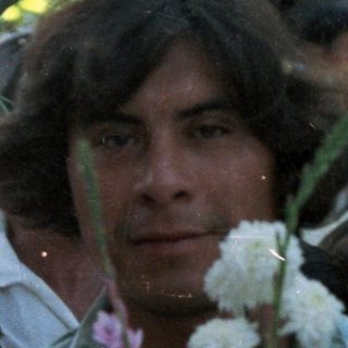 Group of people holding candles and flowers in a procession.