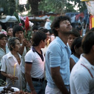 People gathered, holding candles, seemingly in a procession.