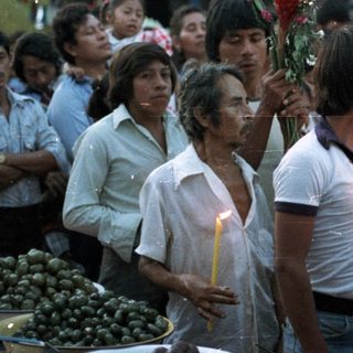 People gathered, holding candles, seemingly in a procession.