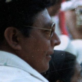 People hold candles, smiling, in a crowd scene.