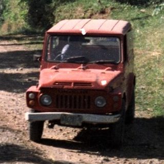 Road, vehicle, and person amidst lush, hilly landscape.