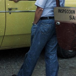 Men converse near a yellow truck with inspection signage.