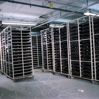 Film canisters stacked in rows within a large, industrial storage room.