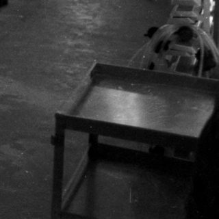 Factory worker in a room with automated painting equipment.