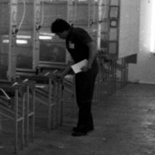 Factory worker in a room with automated painting equipment.