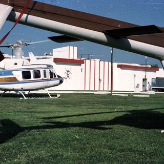 Helicopter sits on grass near a building with decorative facade.