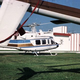 Helicopter sits on grass near a building with decorative facade.