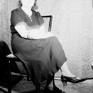 Here's a brief summary of the image: Woman seated in a chair, viewed from the knees down.