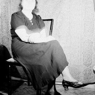 Here's a brief summary of the image: Woman seated in a chair, viewed from the knees down.