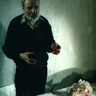 Man holding meat in a presumably butcher's workspace.