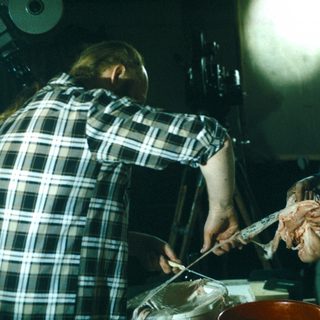 Man cuts meat with knife in a kitchen setting.