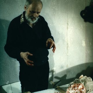 Man examining a bloody, dissected animal brain.