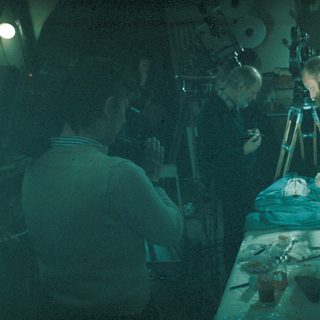 Here's a brief summary of the image: Scientists examining a preserved head under bright light.