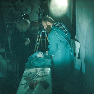 Here's a brief summary of the image: Scientists examining a preserved head under bright light.