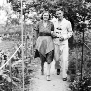 Couple walking along a path in a garden.