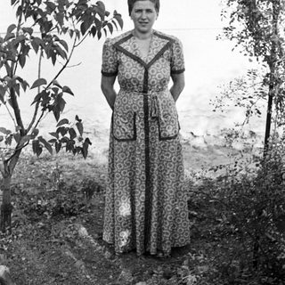 Woman stands outdoors wearing a patterned, long-sleeved dress.