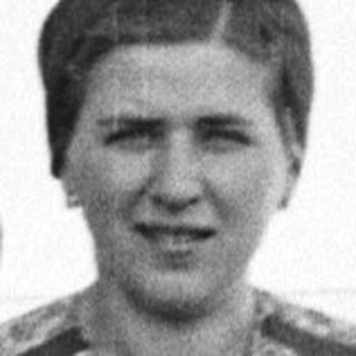 Woman stands outdoors wearing a patterned, long-sleeved dress.