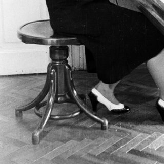 Woman sits at a piano playing in a room.