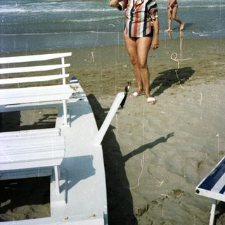 People on a beach with ocean and beach chairs.