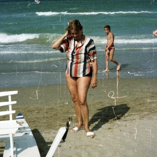 People on a beach with ocean and beach chairs.