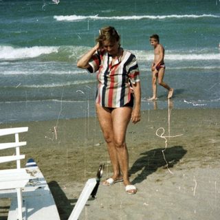 People on a beach with ocean and beach chairs.