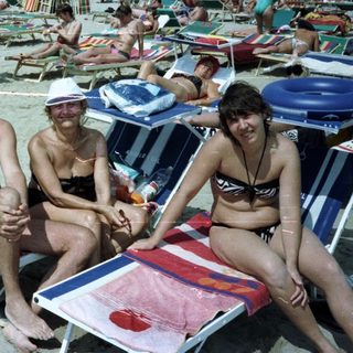 Group of people relaxing and sunbathing on a crowded beach.