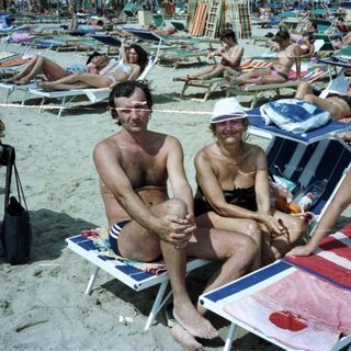 Group of people relaxing and sunbathing on a crowded beach.