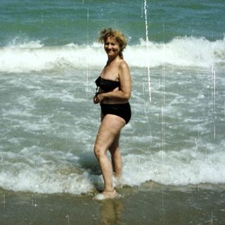 Woman stands in the surf on a sunny beach.