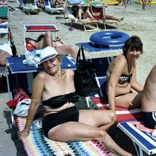 People relaxing on a crowded beach with a sea view.